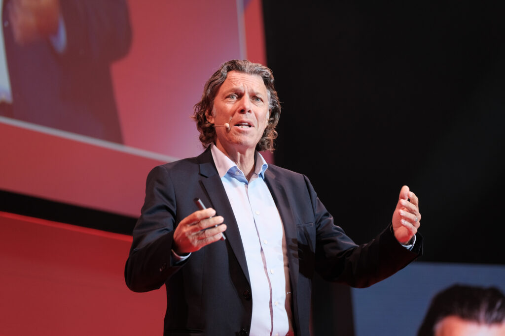 Urs Meier mit offenen Armen sprechend, Konferenzfotograf Stuttgart Leadership-Vortrag #nxtKNOWLEDGE 2025.