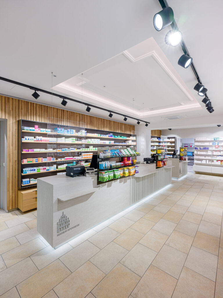 Heller Verkaufsraum mit zentralem HV-Tresen und LED-Unterbeleuchtung – Architekturfotograf dokumentiert Apothekenumbau
