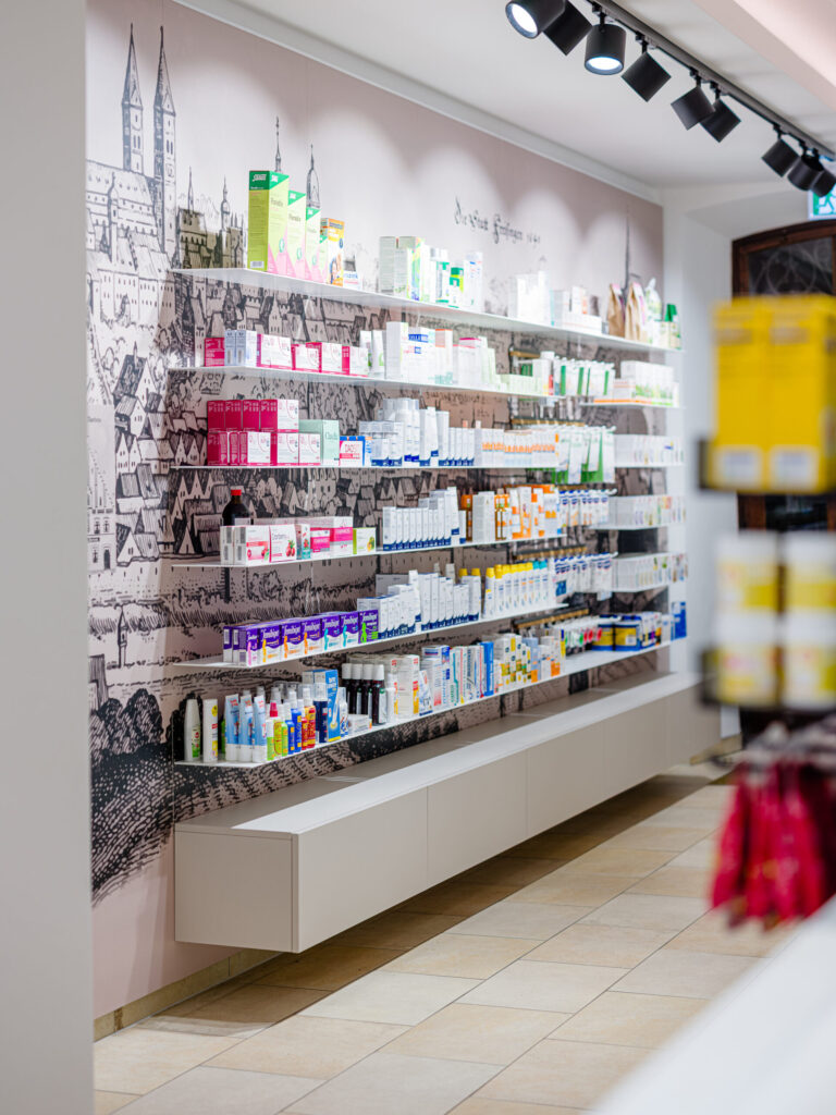 Regalwand mit beleuchteten Produktpräsentationen – modernes Interior Design im Apothekenumbau der Marienapotheke Freising