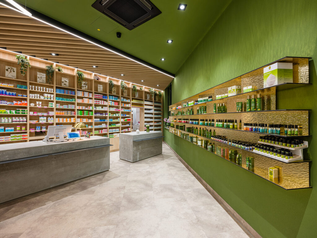 Moderner Verkaufstresen in Beton-Optik vor grüner Wand, Interior Design Apotheke Vilshofen.