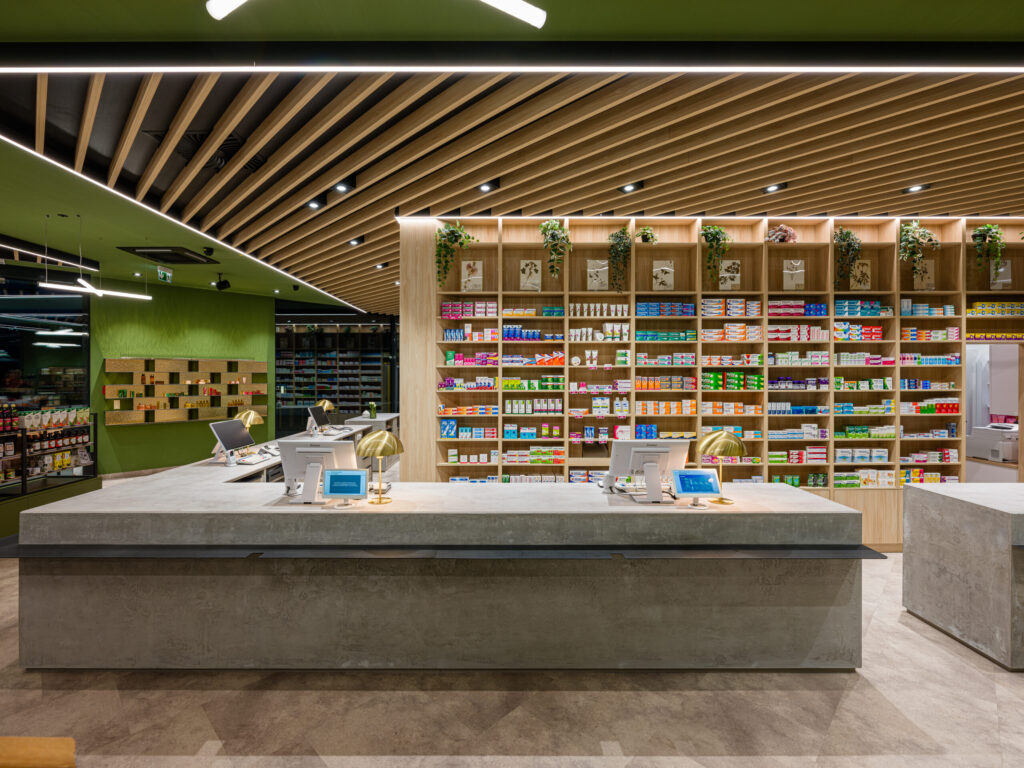 Panorama-Ansicht der Postapotheke mit Fokus auf Lichtdesign und grüne Deckenfarben.