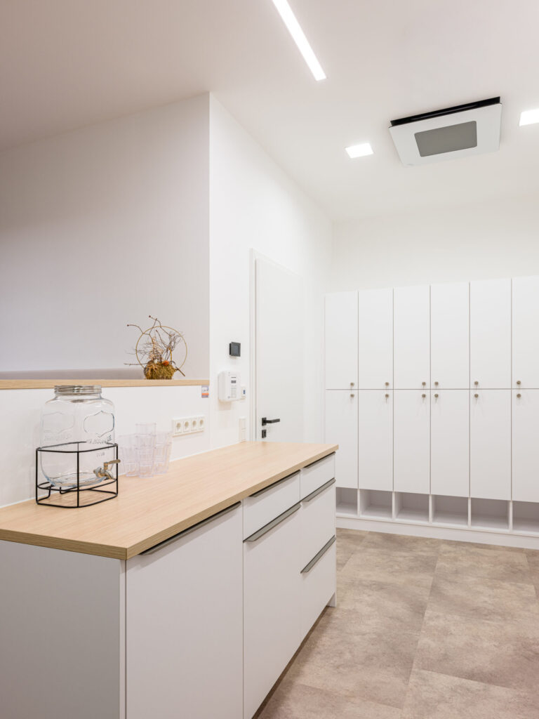 Cleanes Design im Personalbereich, weiße Schränke und helle Holzelemente.