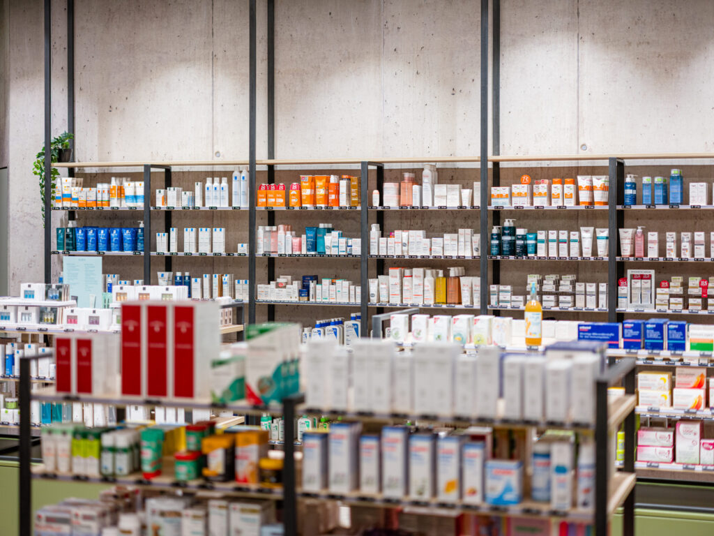 Strukturierte Warenregale aus schwarzem Metall vor Sichtbetonwand, Industrial Style.