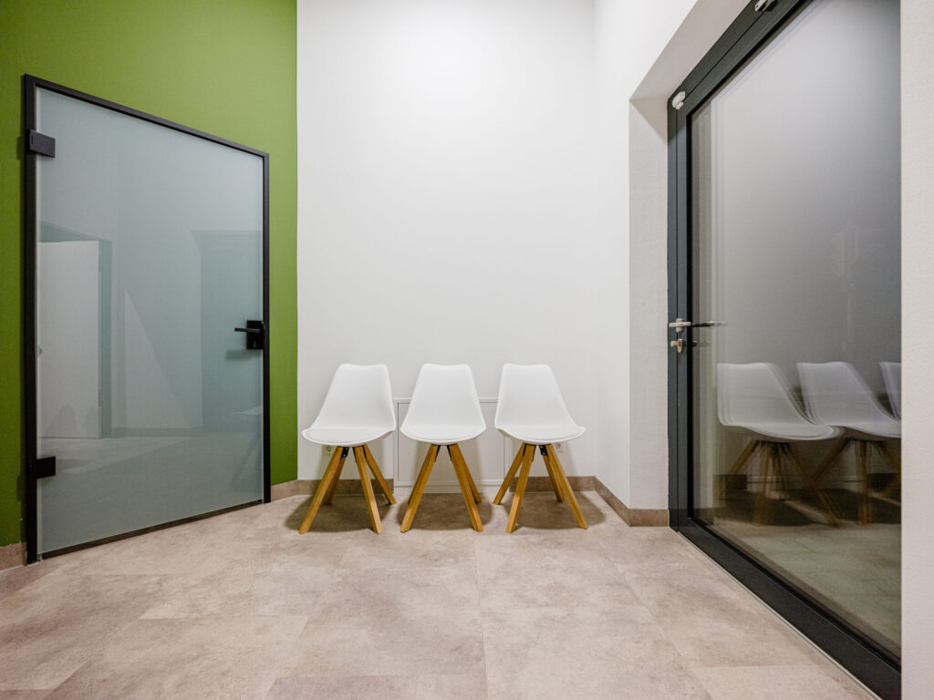 Wartebereich mit ikonischen weißen Stühlen und Glasfront, moderne Raumfotografie.